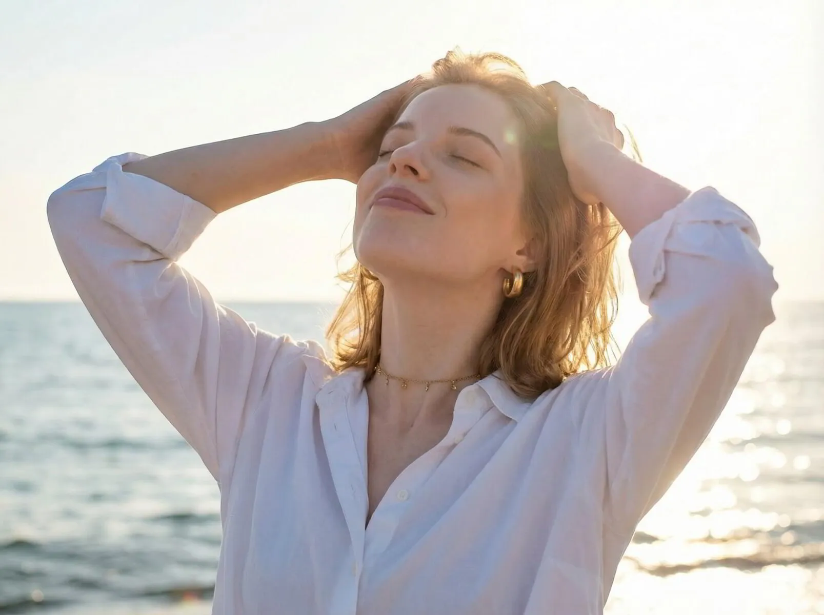 Frau genießt entspannt das Sonnenlicht am Meer als Symbol für hormonelles Wohlbefinden und Vitalität